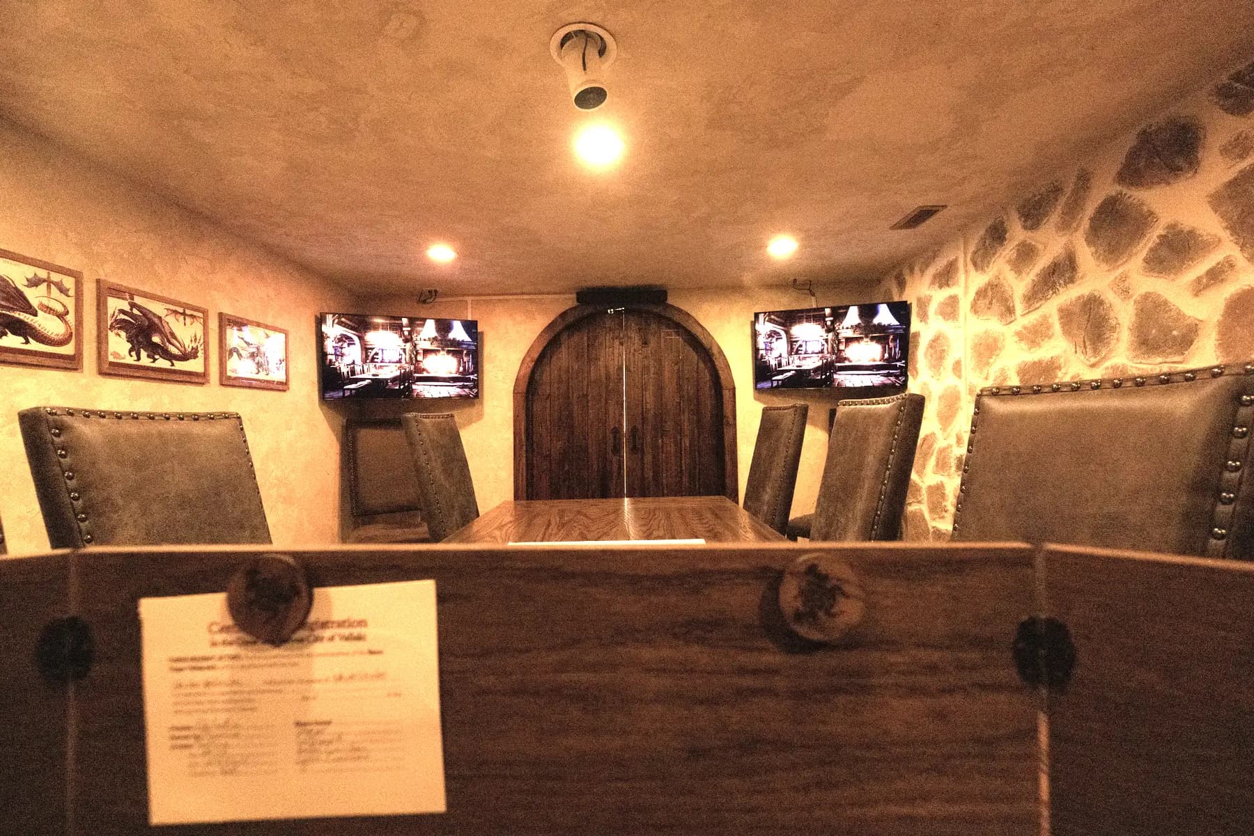 The Dungeon: a long table beneath a stone wall, its screens lit, behind an arched wooden door
