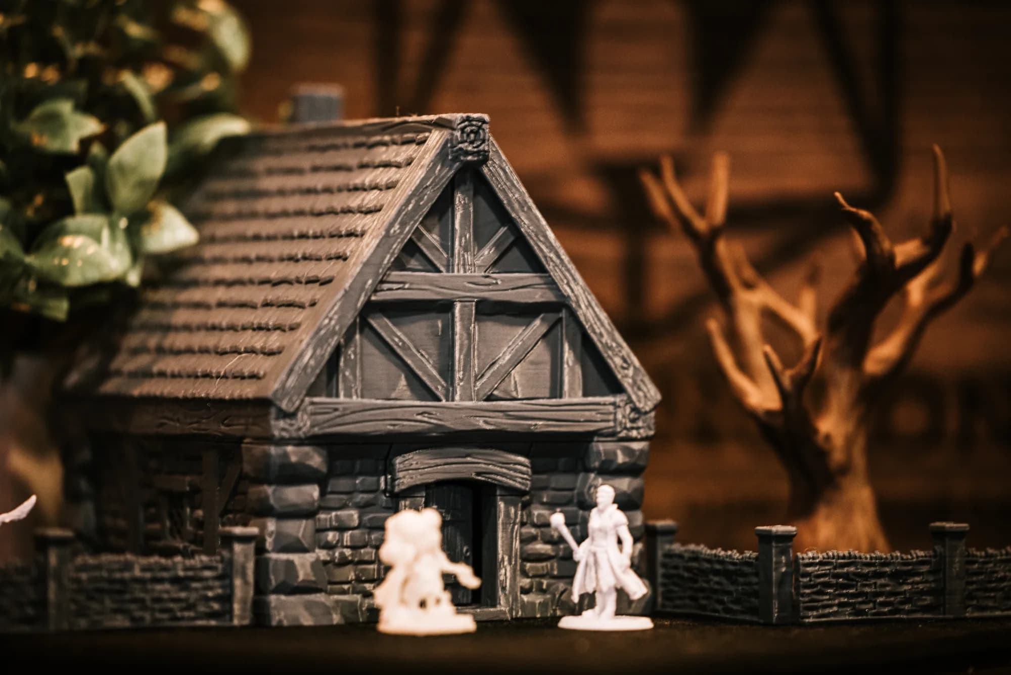 A 3D printed timber-framed house with two unpainted printed figures outside it